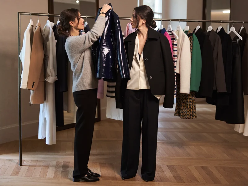 Stylist holder en jakke op mod kundens skulder for at vurdere pasform